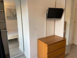 een kamer met een tv, een dressoir en een spiegel bij Cosy bedroom with bathroom en suite in London Canary Wharf E14 in Londen