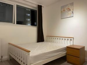 een slaapkamer met een wit bed en een raam bij Cosy bedroom with bathroom en suite in London Canary Wharf E14 in Londen