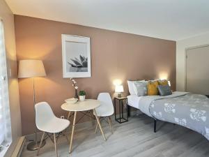 een slaapkamer met een bed en een tafel en stoelen bij The Sunbeam in Mont-Tremblant