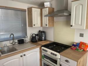 a kitchen with white cabinets and a stove top oven at Gold star 6 birth caravan in Berrow
