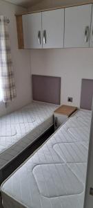 an empty room with two beds and a cabinet at Gold star 6 birth caravan in Berrow