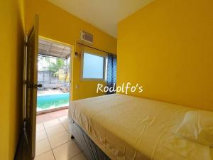 1 dormitorio con 1 cama en una pared amarilla en Rodolfo's Hermosa propiedad en playa La Varona, Tulate, en Mazatenango