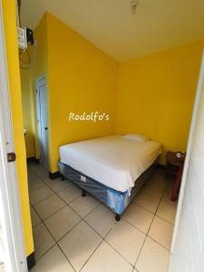 1 dormitorio con 1 cama en una pared amarilla en Rodolfo's Hermosa propiedad en playa La Varona, Tulate, en Mazatenango