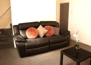 a black leather couch with pillows on it in a living room at AmazenHome - Stylish 3 bed - House of Ebony in Leigh