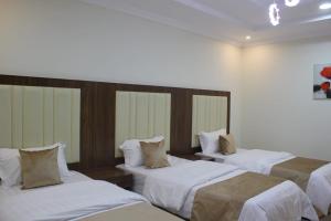 a room with three beds with white sheets at زد z الجوهرة للشقق المخدومة in Al Jāmi‘ah
