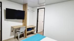 um quarto com uma cama e uma televisão na parede em Hotel Monarka-Edificio em Popayán