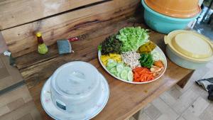 eine Schüssel Salat auf einem Holztisch mit einem Teller in der Unterkunft บ้านระเบียงเลหลังสวน 1 ห้องริมทะเล in Ban Hin Sam Kon