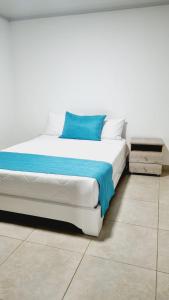 un letto bianco con un cuscino blu sopra di Hotel Monarka-Edificio a Popayan
