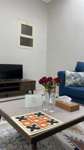 همس المدينة شقة مفروشة في المدينة المنورة: غرفة معيشة مع طاولة قهوة عليها زهور