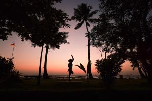 a woman is jumping off a palm tree at sunset at Coconut Lagoon Kumarakom- CGH Earth in Kumarakom