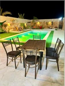 una mesa y sillas frente a una piscina por la noche en شاليه البحر الميت الرامة-Deadsea en Al Rama
