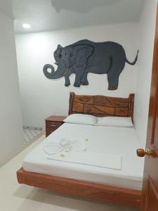 a mural of an elephant on a wall next to a bed at HOTEL EL EMPERADOR in Doradal