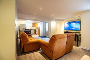 a living room with two chairs and a flat screen tv at L'Oasis Urbaine in Saint-Hubert
