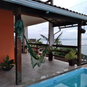 un hamac sur le toit d'une maison avec piscine dans l'établissement Cantinho do paraíso da Deuza, à São Pedro da Aldeia