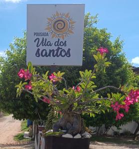 een teken dat zegt wie Santos doet met bloemen bij Pousada Vila dos Santos in Porto De Galinhas