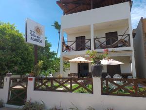 a white building with an umbrella and a restaurant at Pousada Vila dos Santos in Porto De Galinhas