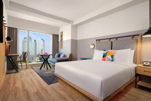 a bedroom with a large white bed and a living room at Moxy Putrajaya in Putrajaya