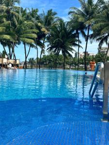 a swimming pool with palm trees and a slide at JATIUCA SUÍTES - BY SLAVIEIRO -Flat 205 in Maceió