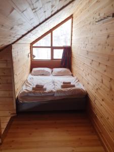 a bed in a wooden room with a window at Kvamskogen & Hardanger Holliday homes in Norheimsund