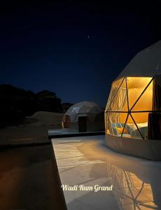 two domed tents are lit up at night at Wadi Rum Grand in Wadi Rum