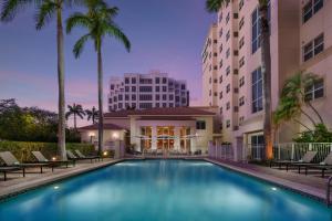 a swimming pool in front of a building with palm trees at Residence Inn by Marriott Miami Aventura Mall in Aventura