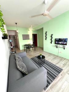 a living room with a gray couch and a television at Seaview Holiday Apartment 3 - WiFi & Netflix in Kuala Terengganu