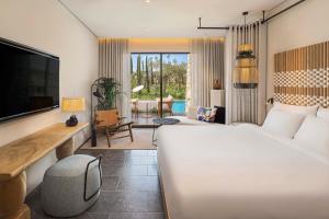 a bedroom with a white bed and a living room at W Costa Navarino in Pylos