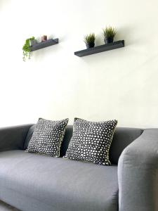 a couch with two pillows and two plants on a wall at Seaview Holiday Apartment 3 - WiFi & Netflix in Kuala Terengganu