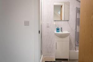 a white bathroom with a sink and a mirror at Stylish Central One Bed Studio in Manchester