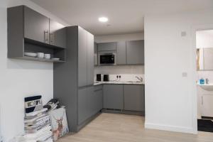 a kitchen with gray cabinets and a sink at Stylish Central One Bed Studio in Manchester