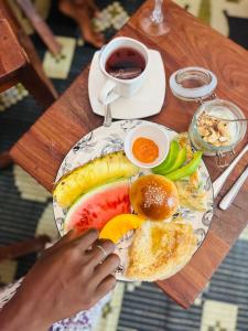 a plate of breakfast food on a wooden table at Binta Boutique Hotel in Nungwi