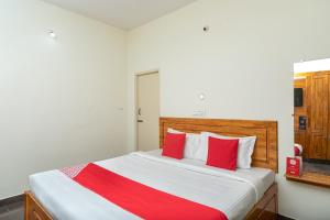 una camera da letto con un grande letto con cuscini rossi di OYO Flagship Thirumala Village Inn a Yelagiri