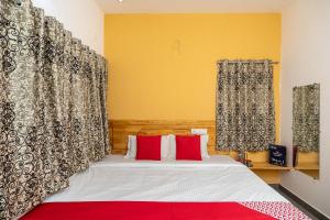 una camera da letto con letto con cuscini e tende rossi di OYO Flagship Thirumala Village Inn a Yelagiri