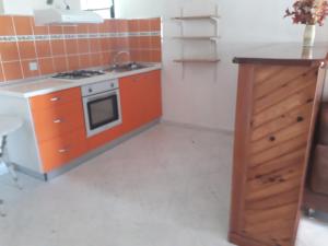 una cucina arancione con piano cottura e mobile in legno di Le Chrinada ad Anse-Bertrand