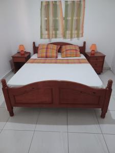 una camera con letto in legno e 2 comodini di Le Chrinada ad Anse-Bertrand