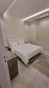a white bedroom with a large bed and a window at فلل شدا ورقان بالهدا in Al Hada