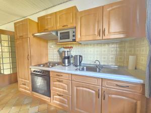 a kitchen with wooden cabinets and a sink and a microwave at Ferienwohnung Deichglück Norddeich in Norden +14 photos
