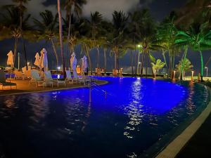 a pool with chairs and palm trees at night at JATIUCA SUÍTES - BY SLAVIEIRO -Flat 205 in Maceió