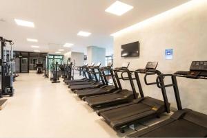 une rangée de tapis de course dans une salle de sport équipée de machines dans l'établissement Apartamento, Centro SP - Piscina e Ar Condicionado, à São Paulo