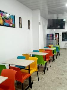 a cafeteria with tables and colorful chairs at HOTEL GLASS LAS VEGAS in La Vega