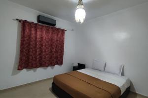 Warzazat Apartments في ورززات: غرفة نوم بسرير وستارة حمراء
