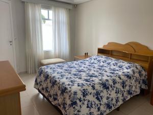 een slaapkamer met een bed met een blauwe en witte deken bij Casa do Jardim in Curitiba