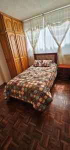 een slaapkamer met een bed met een dekbed en een raam bij Departamento Bien Ubicado con todo lo necesario in Latacunga