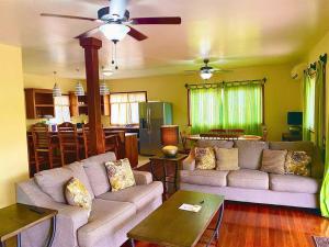 ein Wohnzimmer mit einem Sofa und einem Deckenventilator in der Unterkunft Bahia Vista - Spectacular Views - 4 Bedrooms in Placencia Village