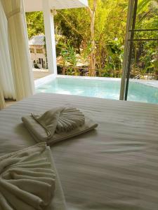 a bed with a pillow on it with a view of a pool at Arb Pa Home and Cafe @ Mae on in Chiang Mai