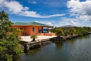 a house next to a body of water at Casa Valencia - Modern Pool Family Luxury Sleeps 8 in Placencia Village