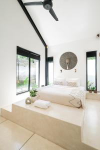 a white bedroom with a large bed and windows at Villa Neptune Uluwatu in Uluwatu