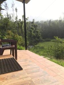 a bench sitting on a patio with a view of a field at Nature stream homestay in Attigundi