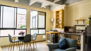 a living room with a table and chairs and windows at Selva House in Medellín