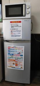 Un four micro-ondes est installé au-dessus d'un réfrigérateur. dans l'établissement 風車村2-1-21号, à Aiba